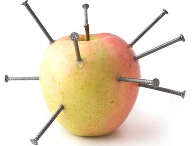 Ein Apfel, in dem Eisennägel stecken